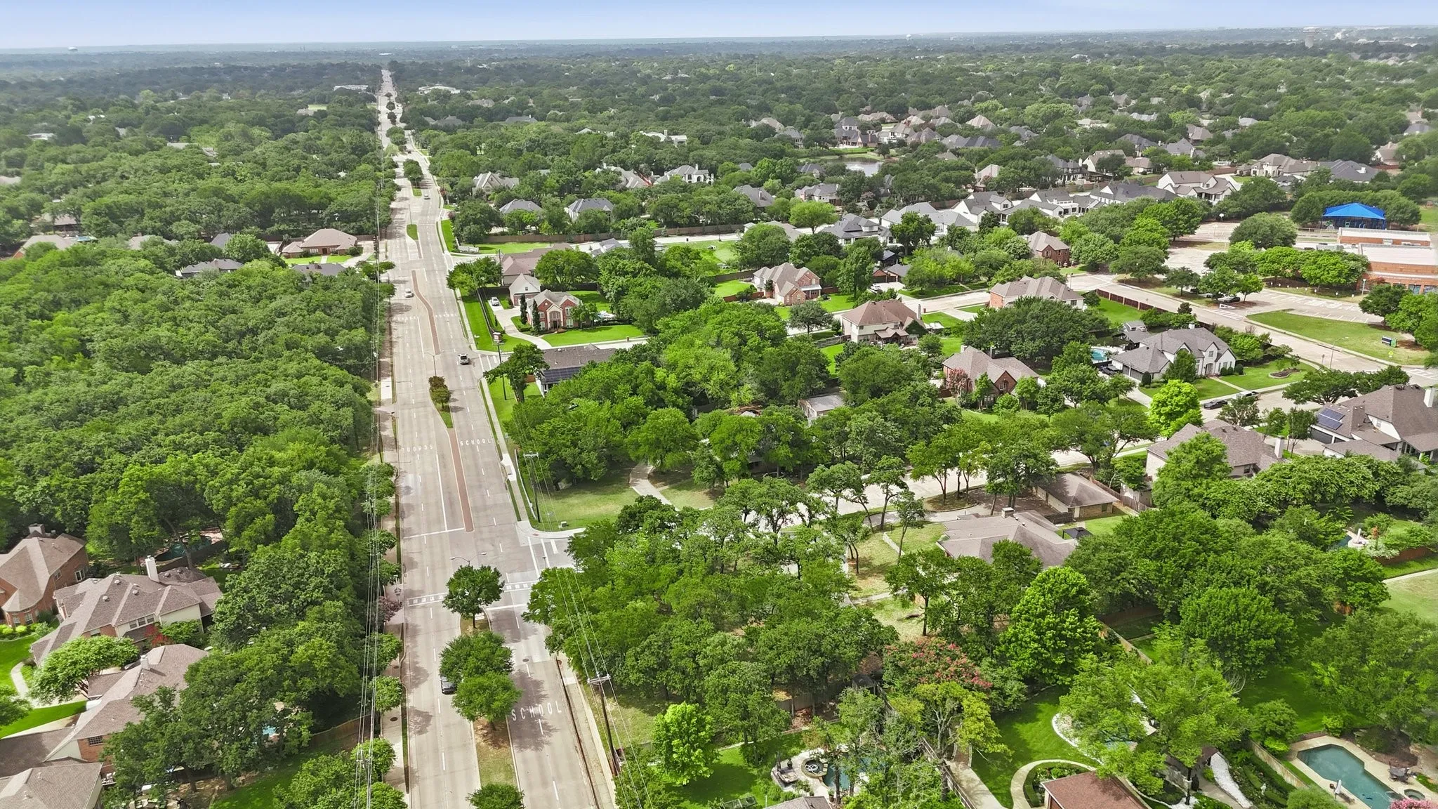 Expansive aerial capturing a tree-lined residential area with numerous single-family homes