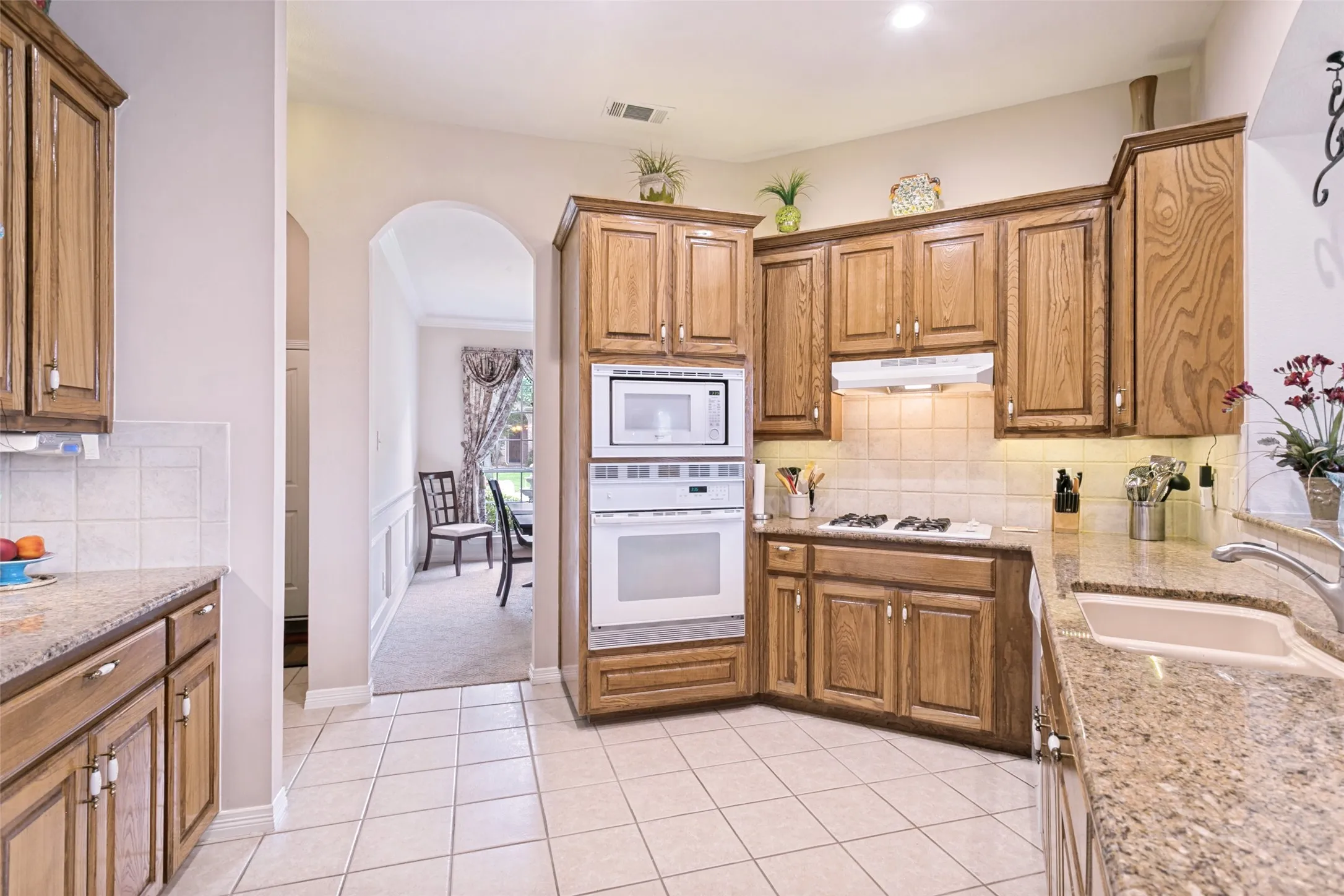 Kitchen featuring wood cabinetry, granite-finish countertops, and a tile backsplash