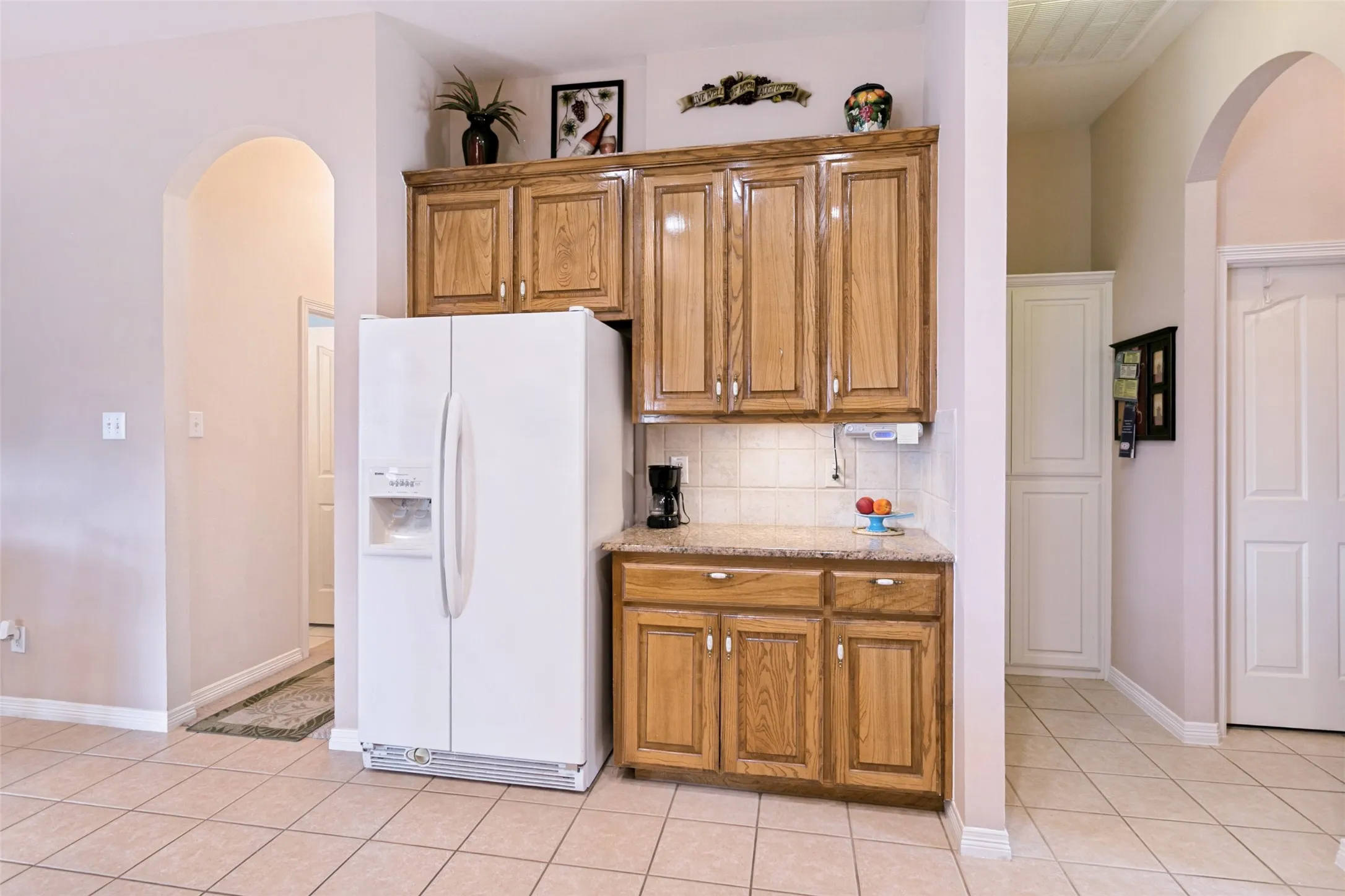 Kitchenette area featuring wood cabinetry, a light-toned countertop, and tile flooring