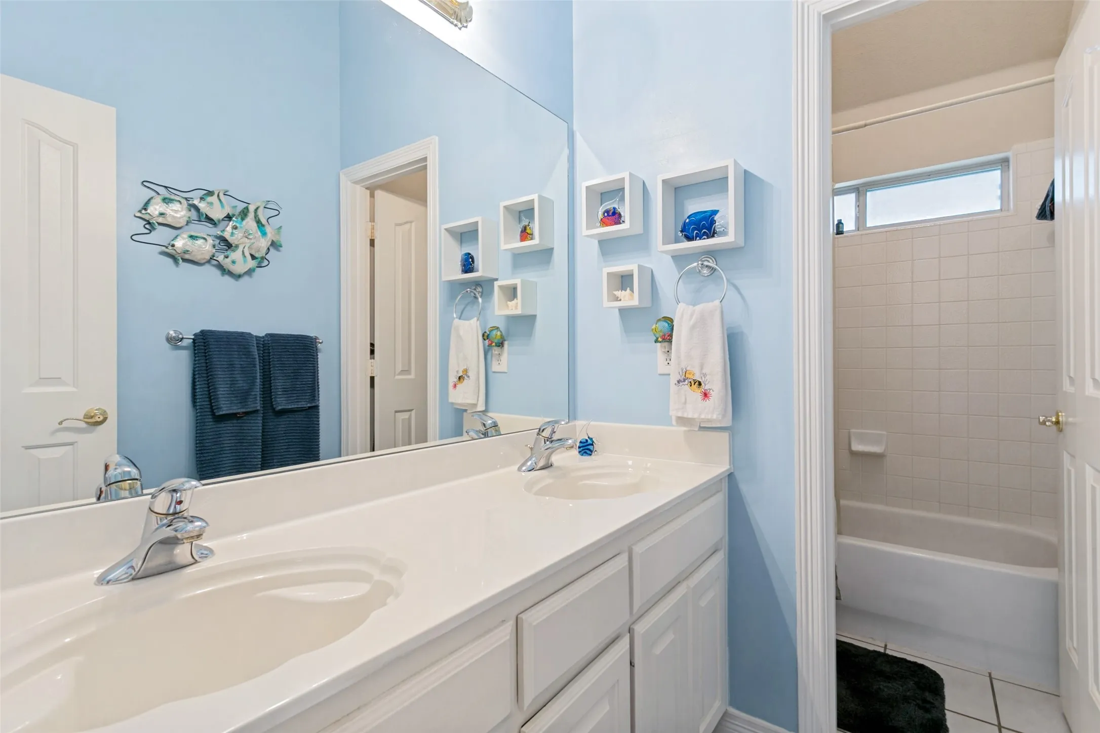 Bathroom featuring a dual-sink vanity with white cabinetry, a large wall-mounted mirror, and a chrome faucet
