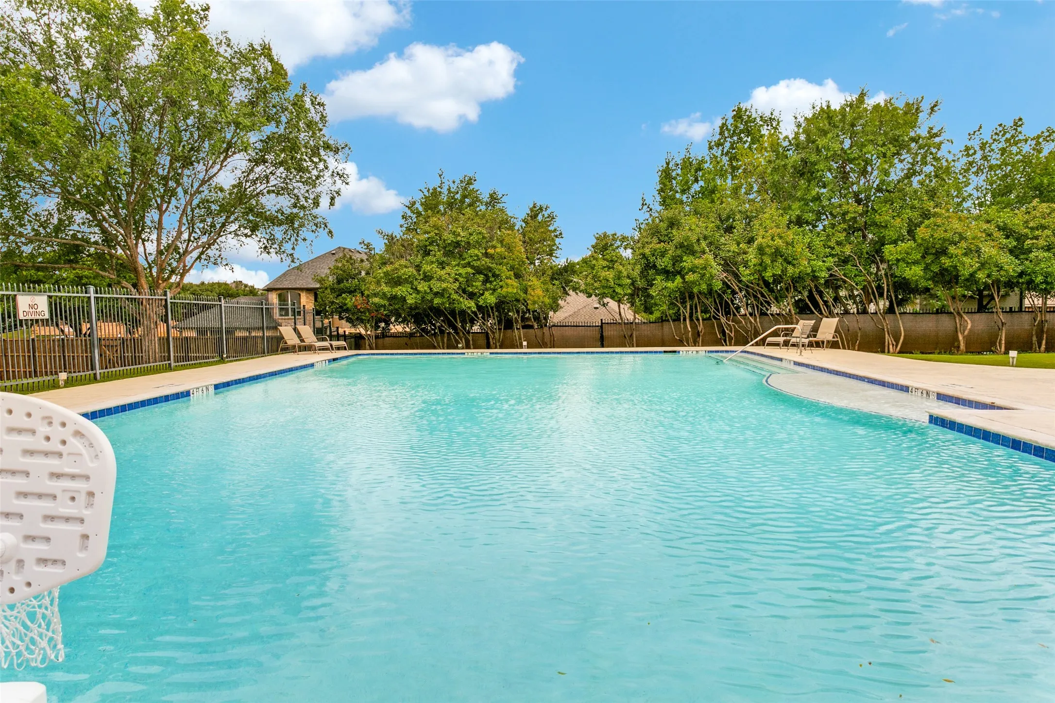 Expansive outdoor Community swimming pool featuring a tiled perimeter, integrated steps, and a surrounding concrete deck