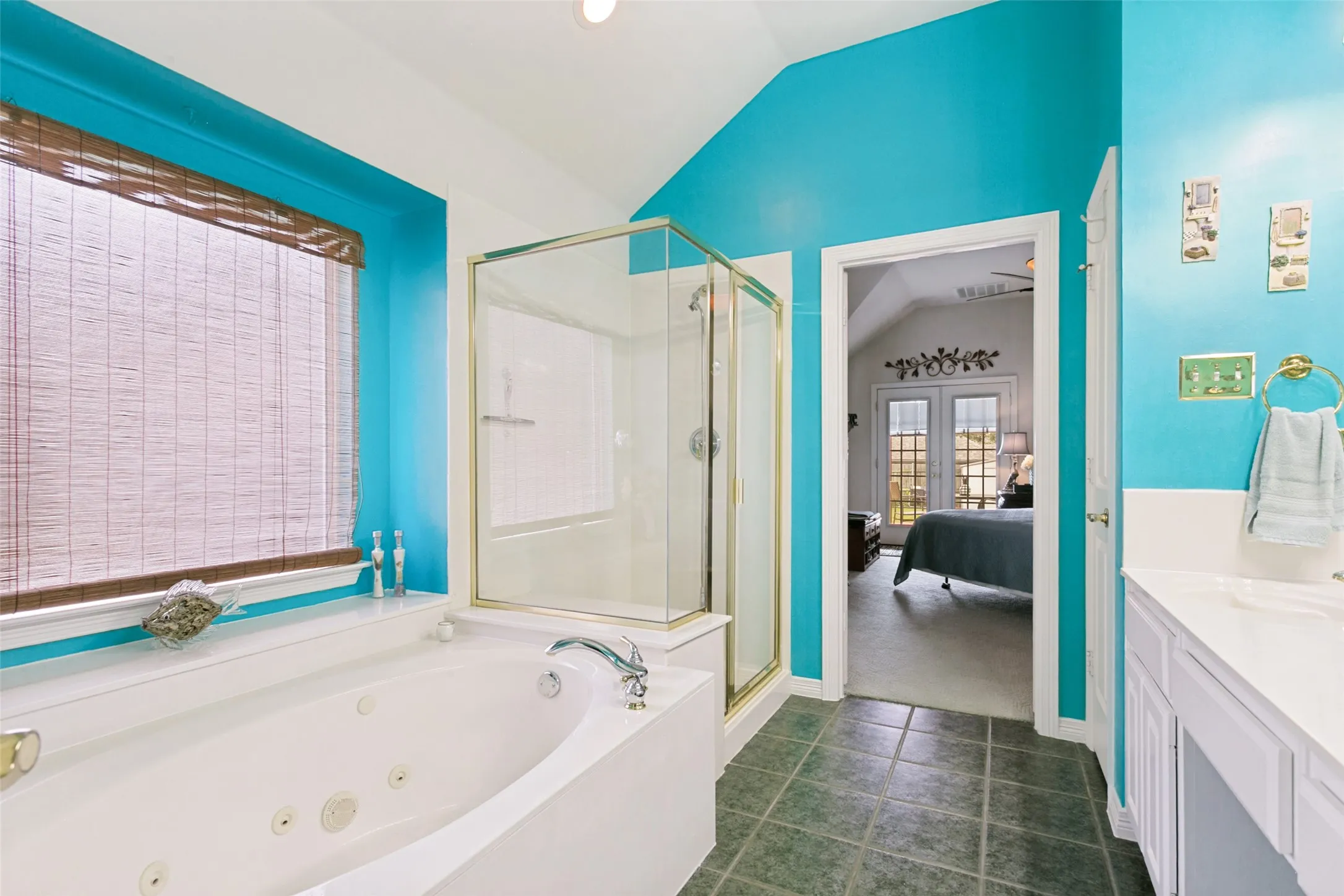 Bathroom featuring a jetted soaking tub, glass-enclosed shower, and a vanity with an integrated sink