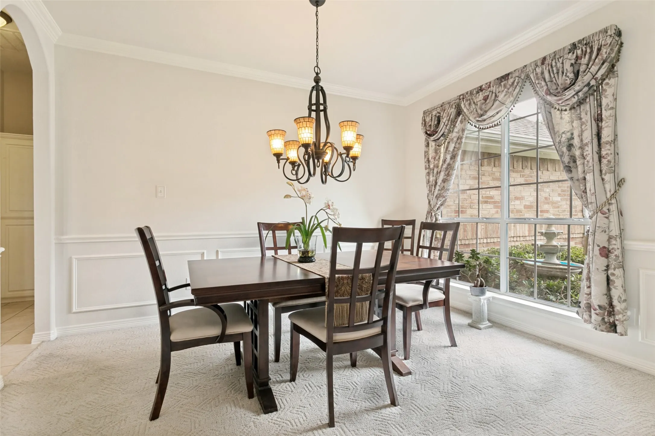 Formal dining area featuring an ornate chandelier, decorative wainscoting, crown molding, and a large bay window