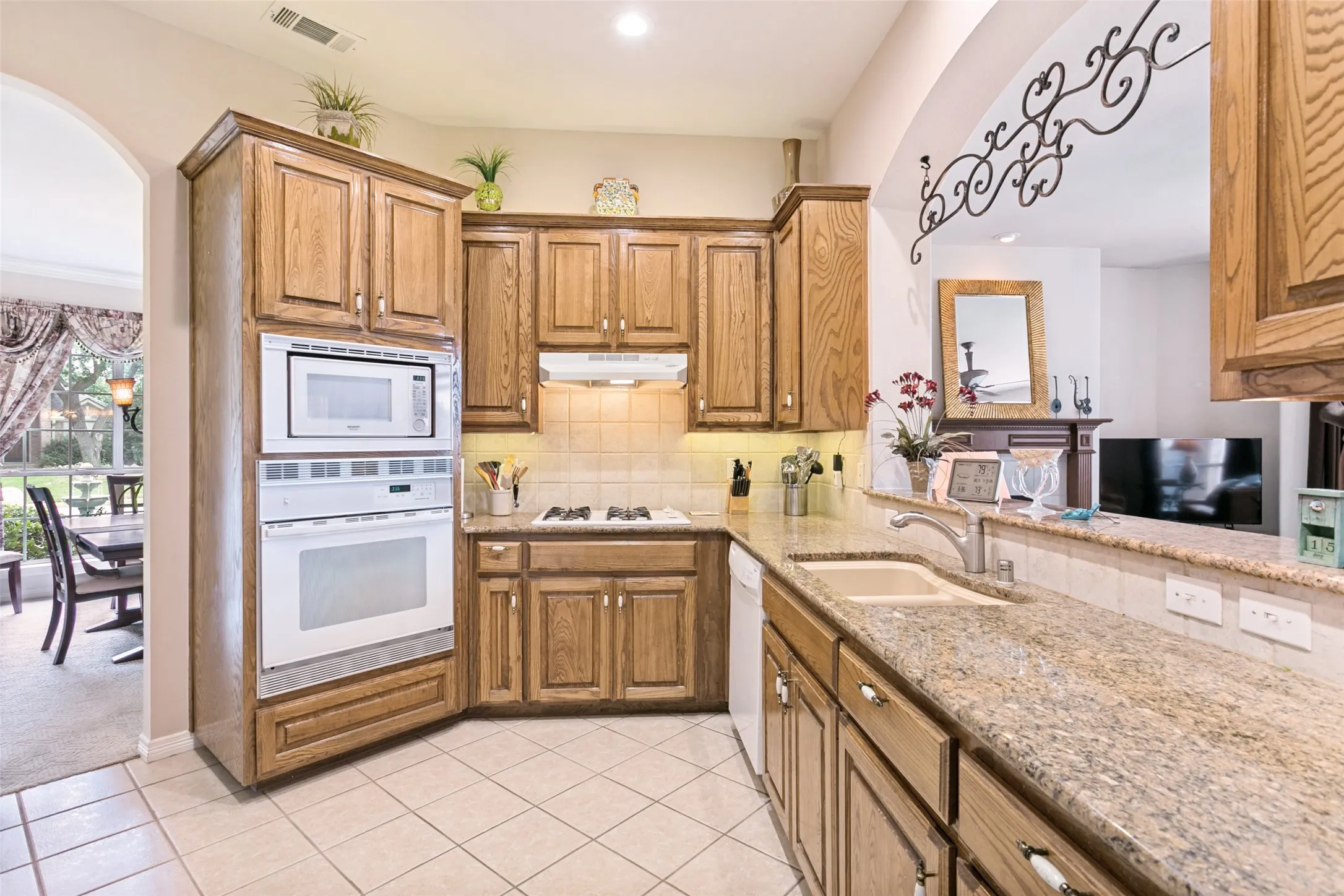 Kitchen featuring wood cabinetry, light-colored tile flooring, and granite countertops