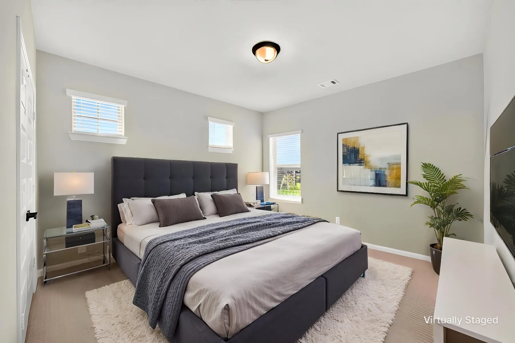 Bedroom featuring light-toned walls, multiple windows with blinds, and a built-in flush mount ceiling light
