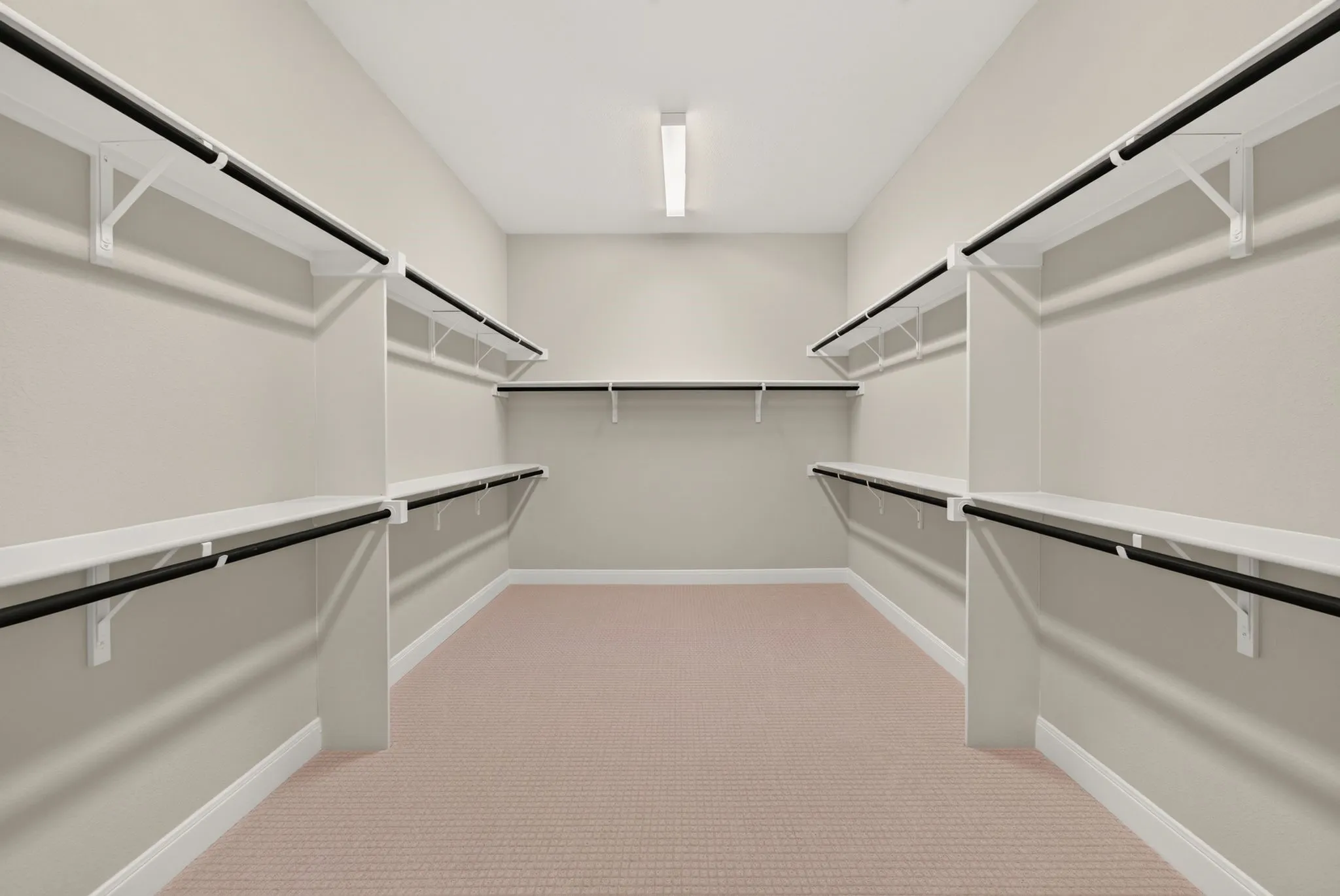 Spacious walk-in closet featuring extensive shelving and multiple hanging rods for comprehensive storage