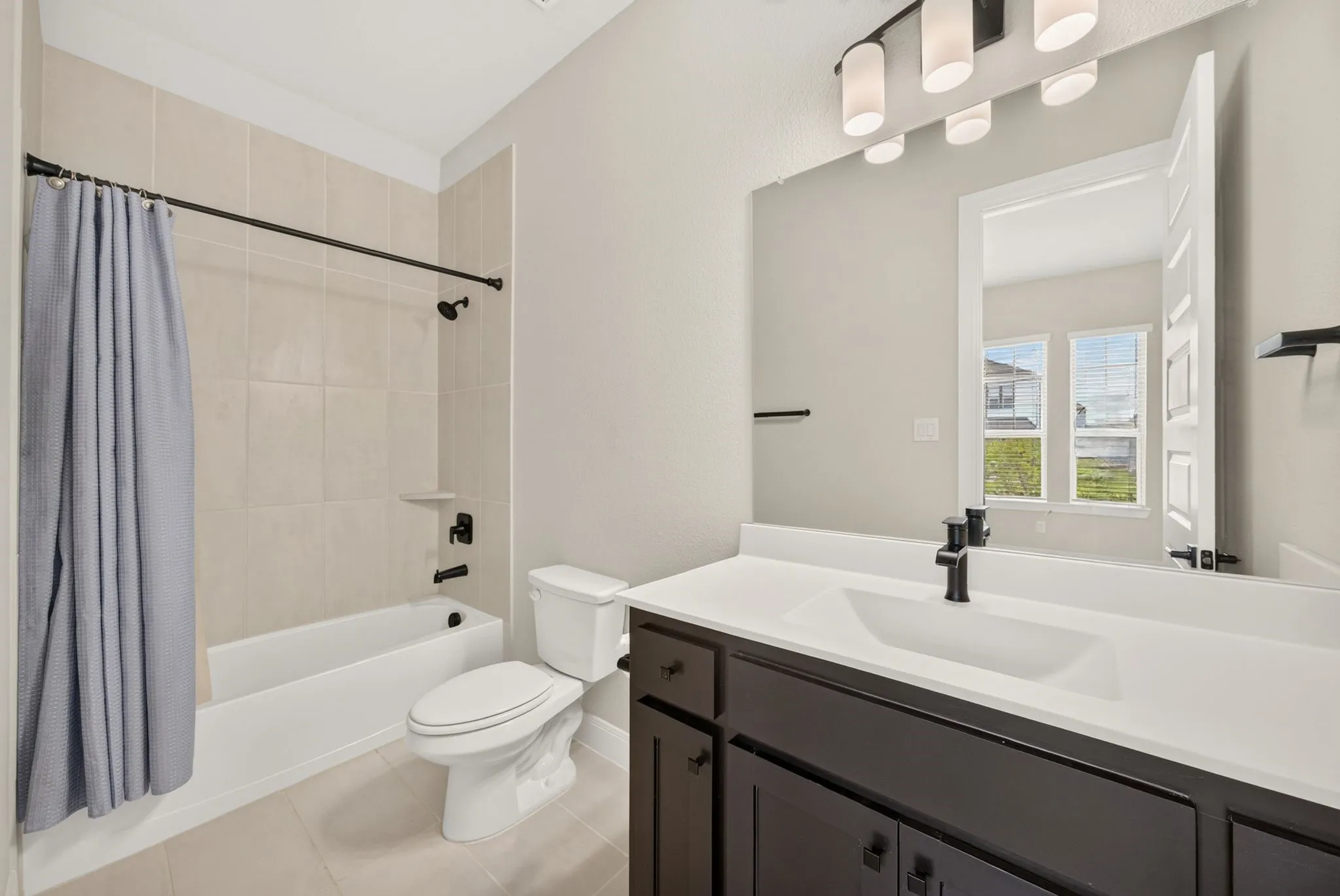 Full bathroom featuring a dark wood-finish vanity with an integrated sink, white countertop, and matte black fixtures