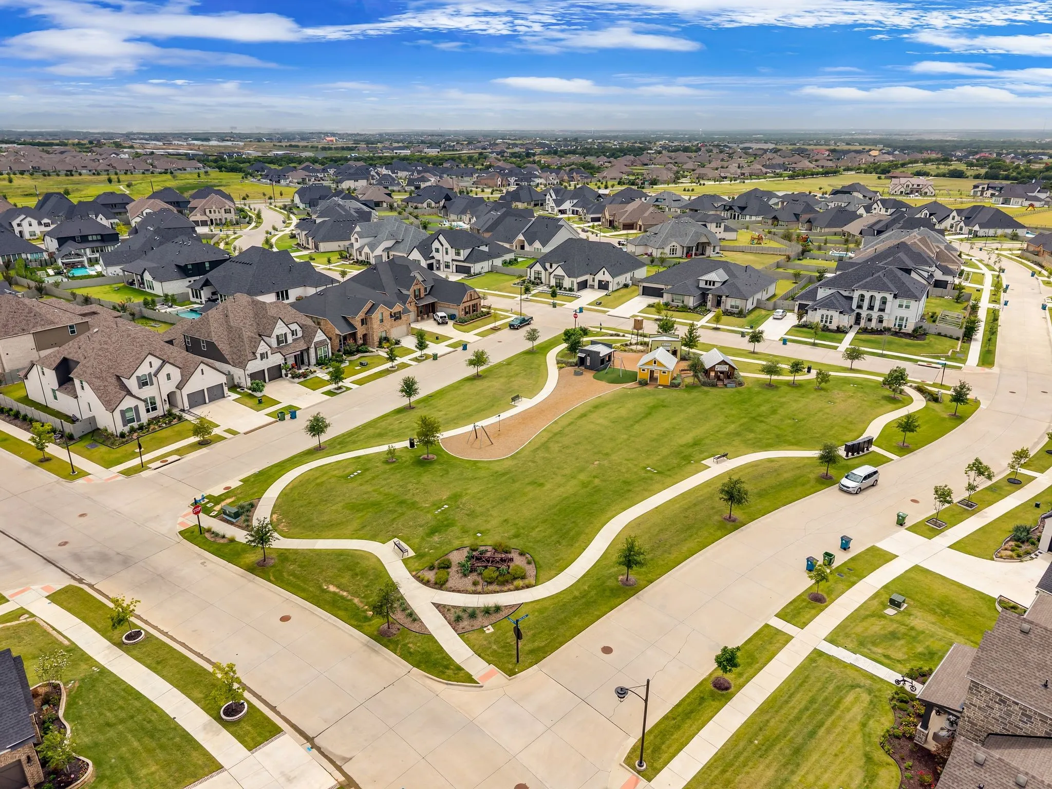 Residential community featuring a central green space with walking paths and recreational equipment