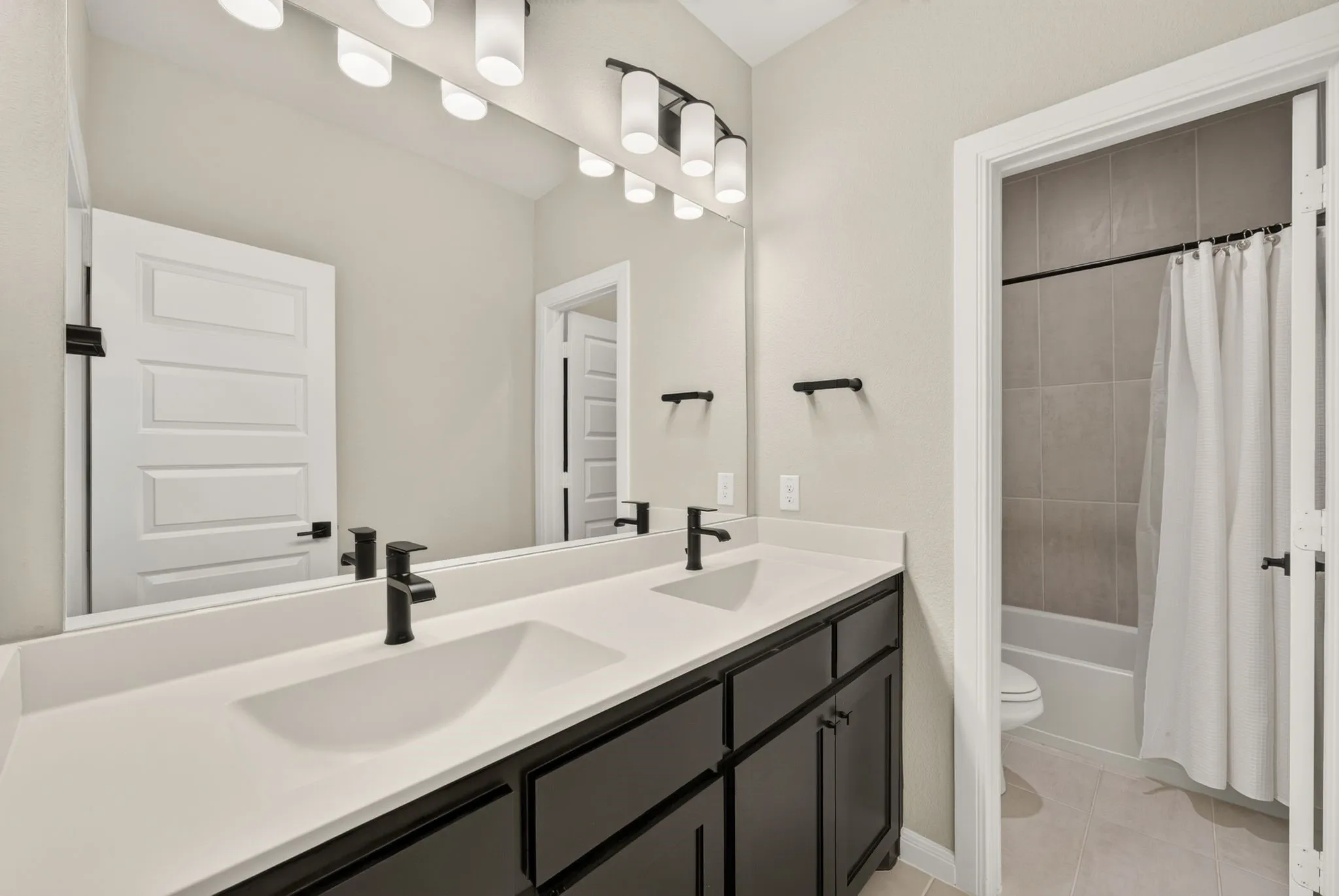 Double vanity with integrated sinks, white countertops, and matte black fixtures