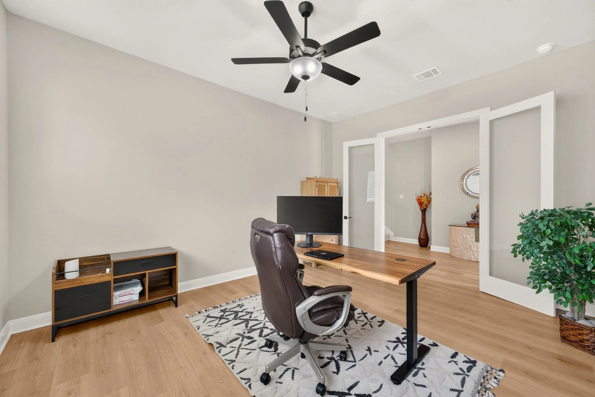 Room featuring light-toned walls, wood-finish flooring, and a ceiling fan with integrated lighting