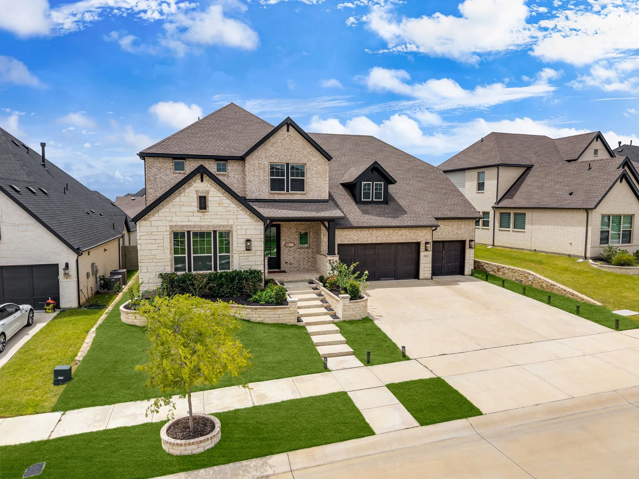 Two-story residence featuring a brick and stone facade, dark shingle roof, and multiple gables