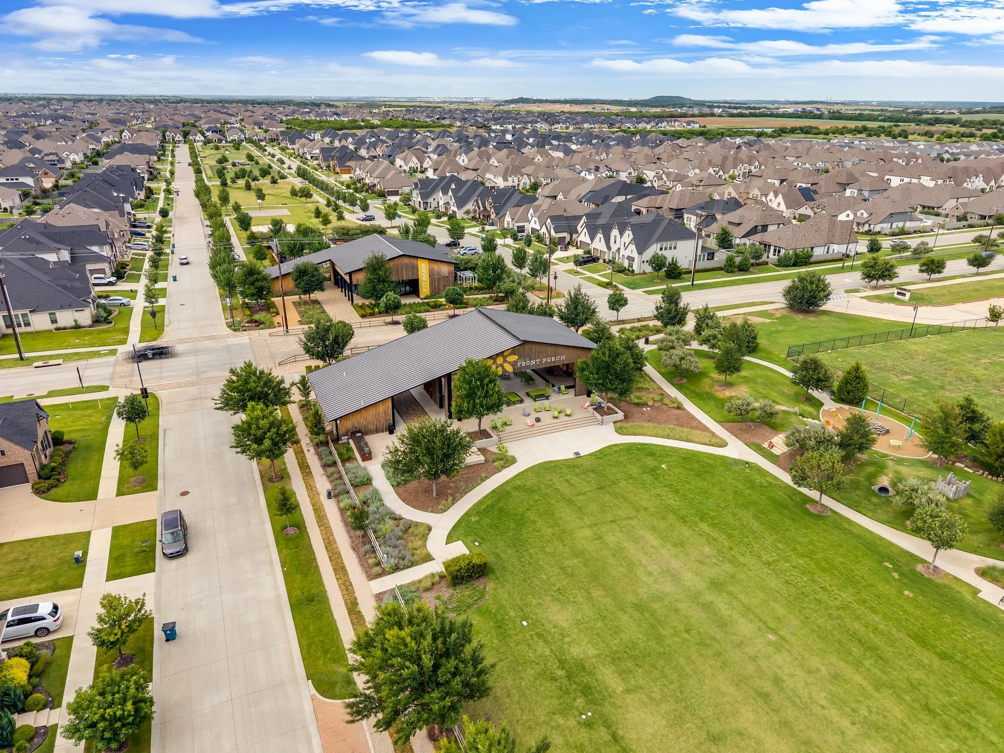 Expansive community green space with manicured lawn areas, established trees, and paved pathways