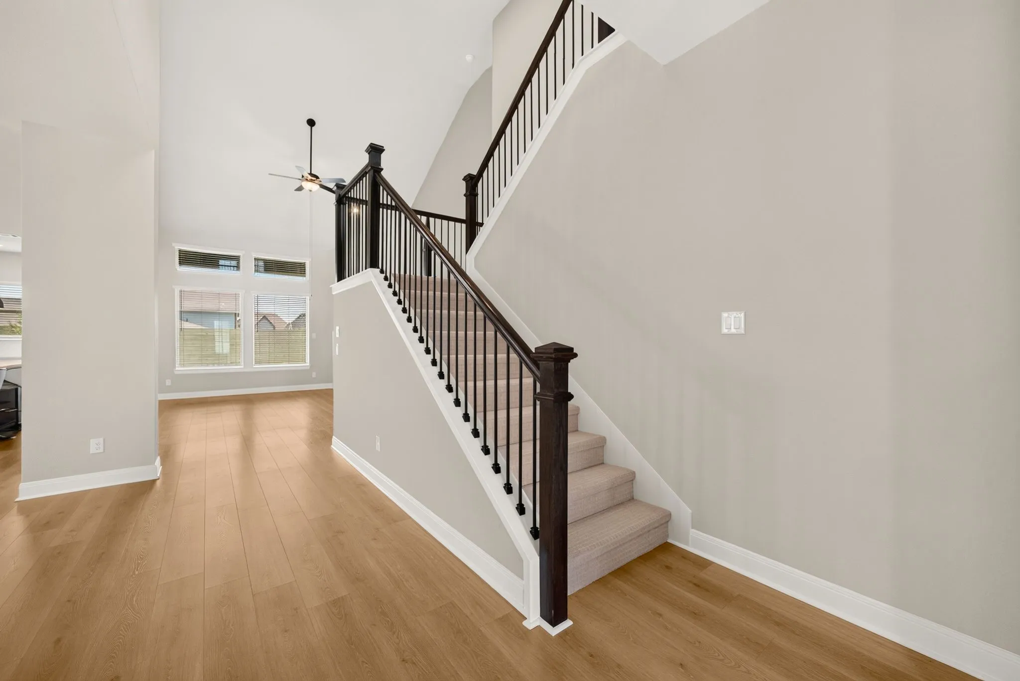 Grand two-story entryway featuring a carpeted staircase with dark wood newel posts and metal balusters
