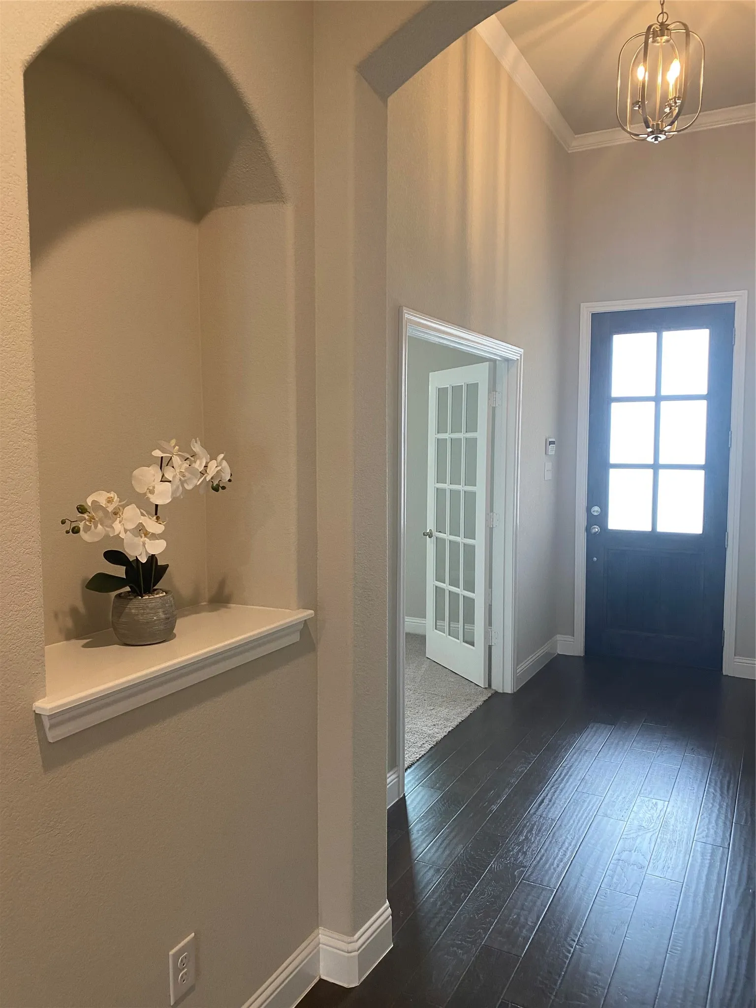 Entrance foyer with wood-type flooring, ornamental molding, and a notable chandelier