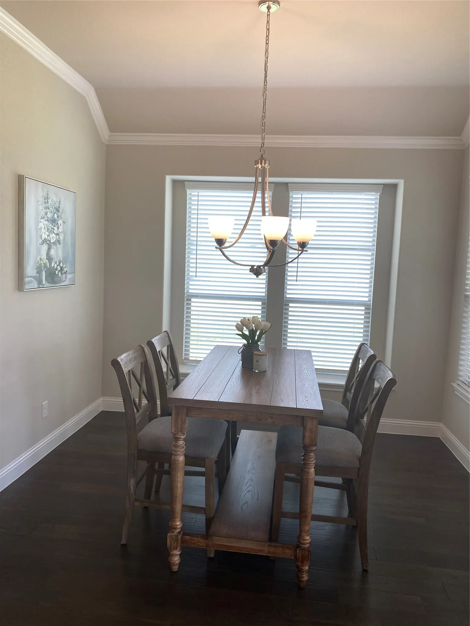 Dining room with an inviting chandelier, dark wood-type flooring, and ornamental molding