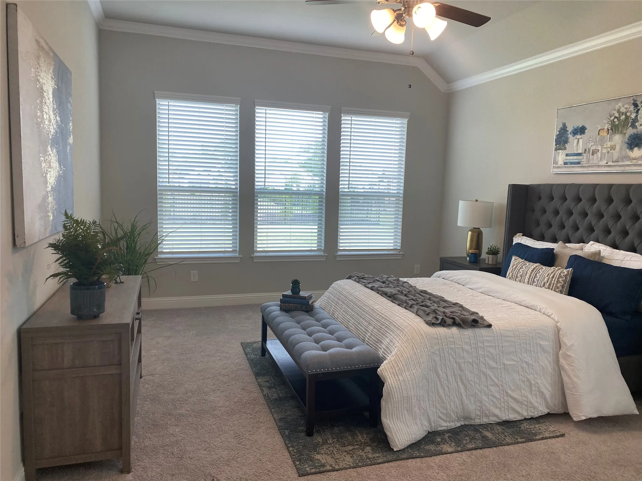 Carpeted bedroom with vaulted ceiling, ceiling fan, and ornamental molding