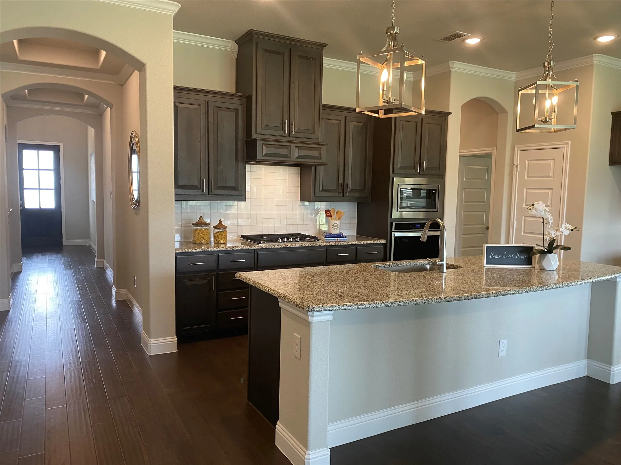 Kitchen with decorative backsplash, dark hardwood / wood-style floors, crown molding, and stainless steel appliances