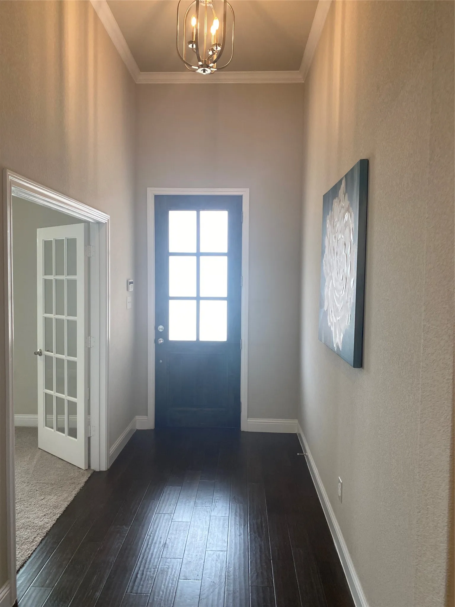 Entryway with dark carpet, a chandelier, and ornamental molding