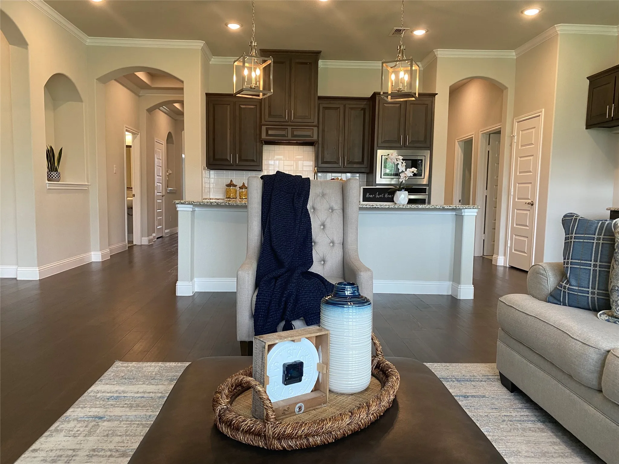 Kitchen featuring tasteful backsplash, stainless steel microwave, crown molding, light stone countertops, and dark hardwood / wood-style flooring