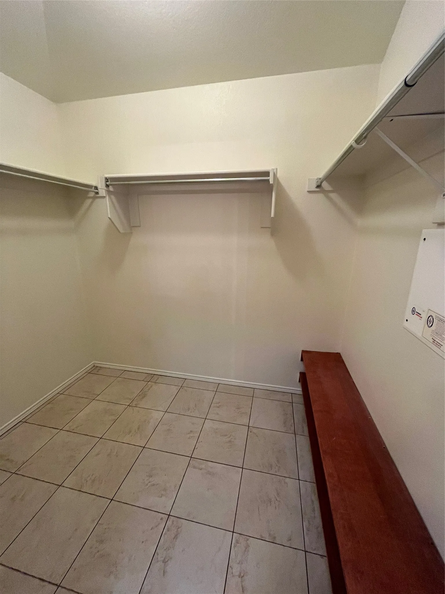 Spacious closet featuring neutral-toned tile flooring, white walls, and multiple built-in shelving units