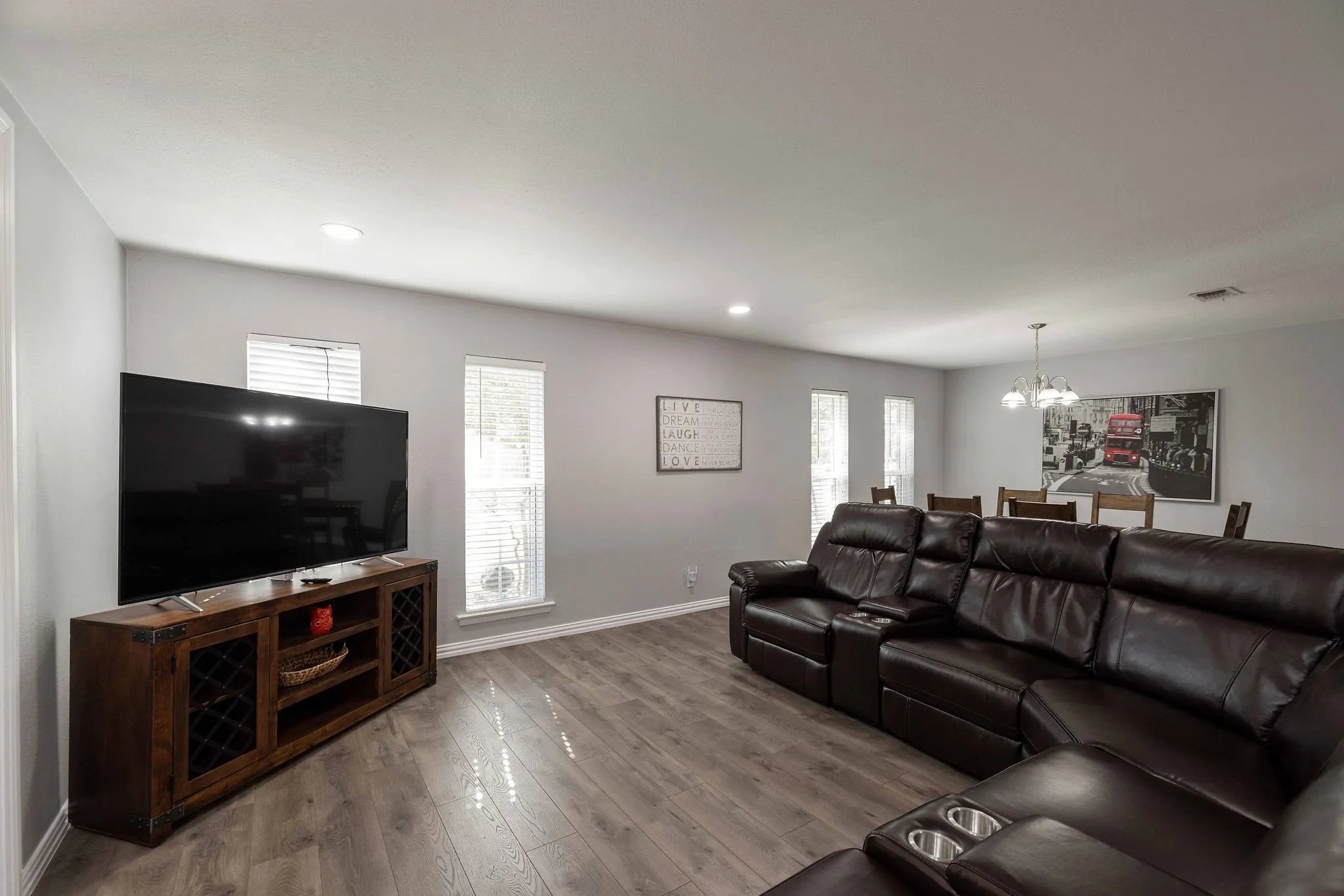 Living room with a chandelier, baseboards, wood finished floors, and recessed lighting