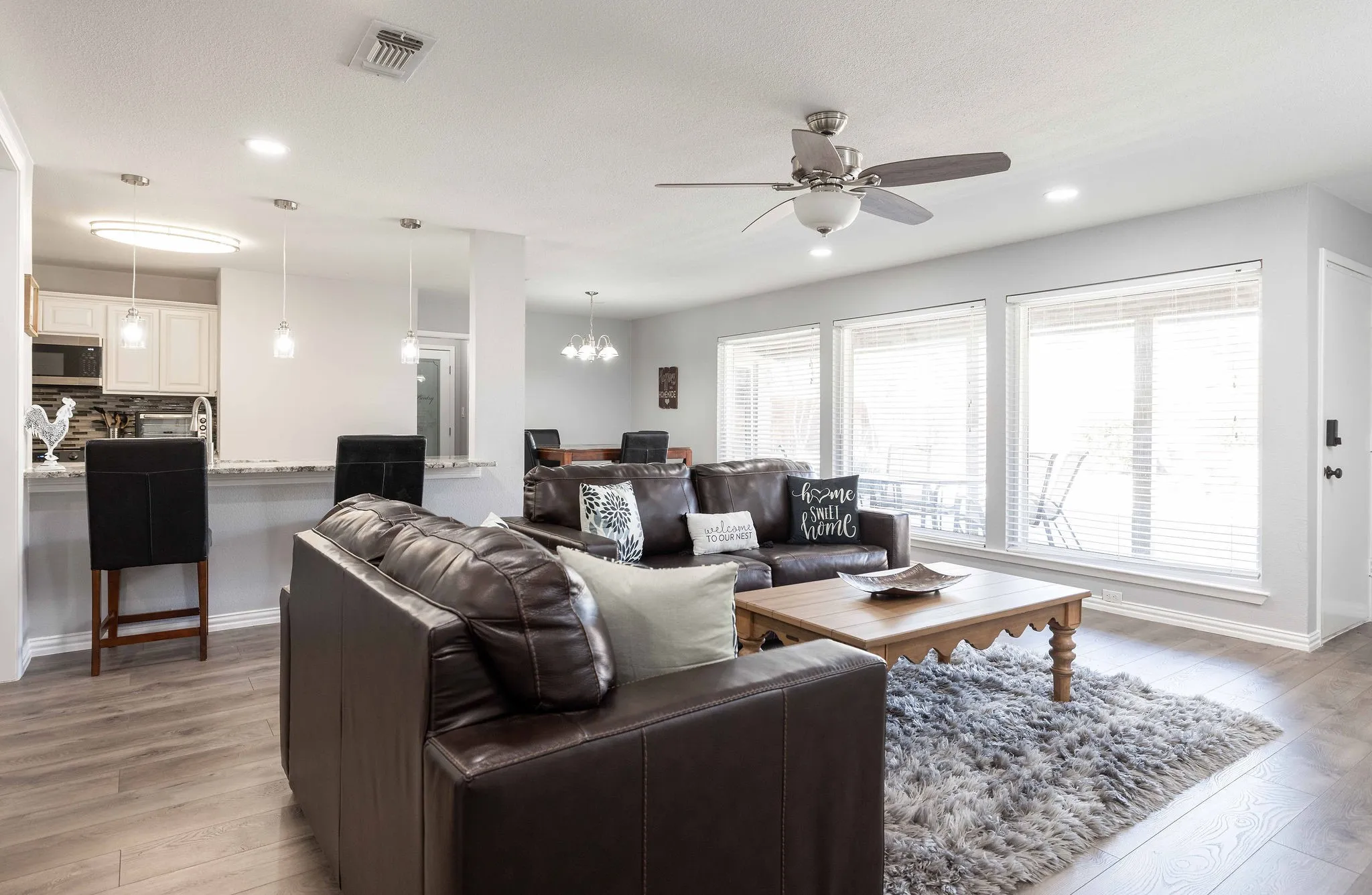 Living room with light wood finished floors, ceiling fan, a chandelier, recessed lighting, and baseboards