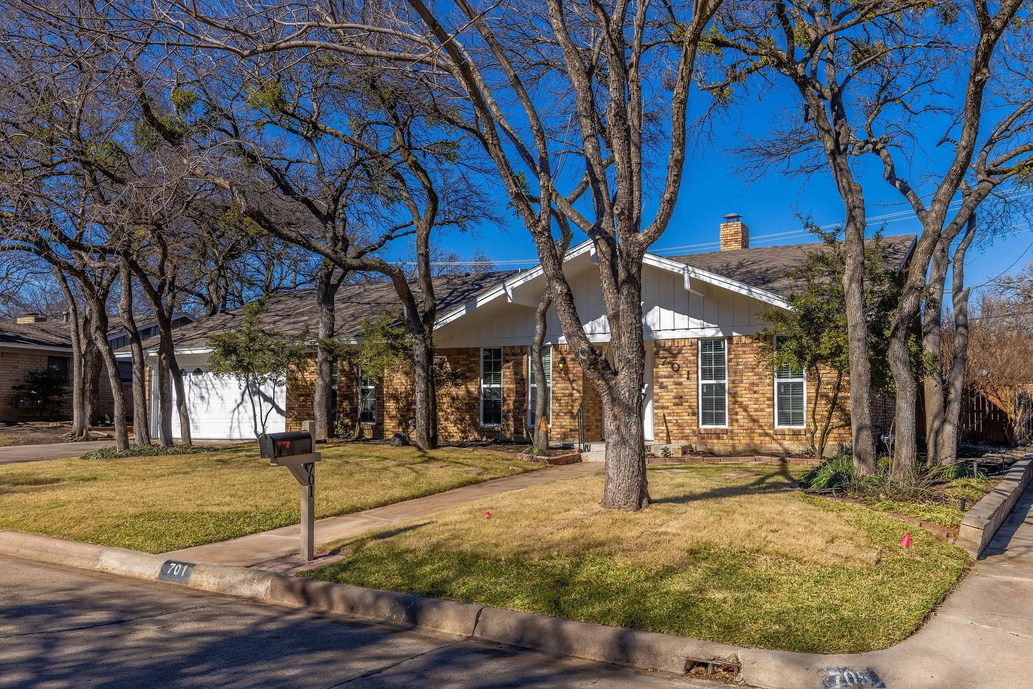 View of front of house featuring brick siding, a chimney, a front lawn, and a garage