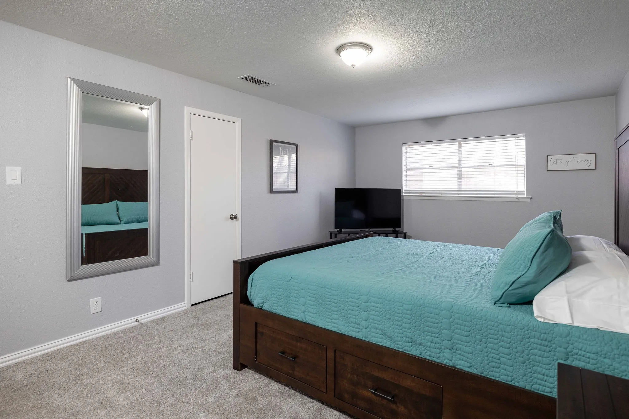 Bedroom with light colored carpet, a textured ceiling, and baseboards