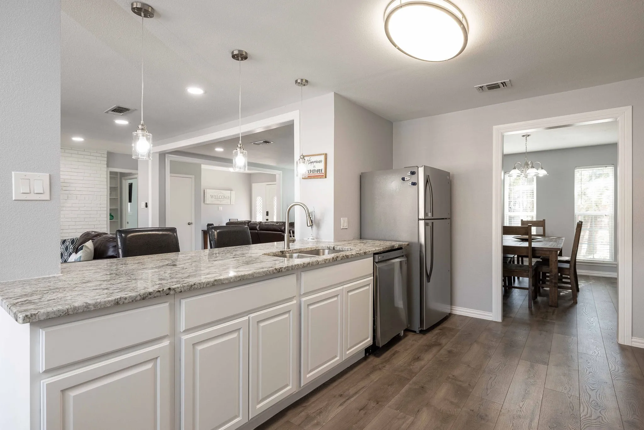 Kitchen with a sink, dishwasher, dark wood-type flooring, open floor plan, and white cabinets