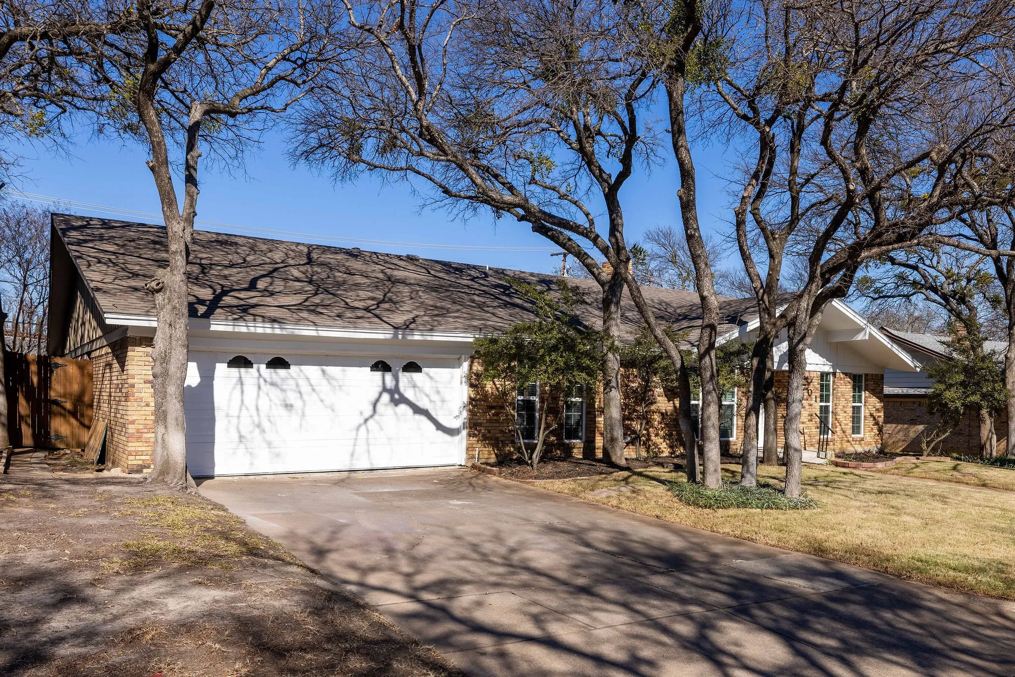View of front of property featuring brick siding, an attached garage, driveway, a front yard, and a shingled roof