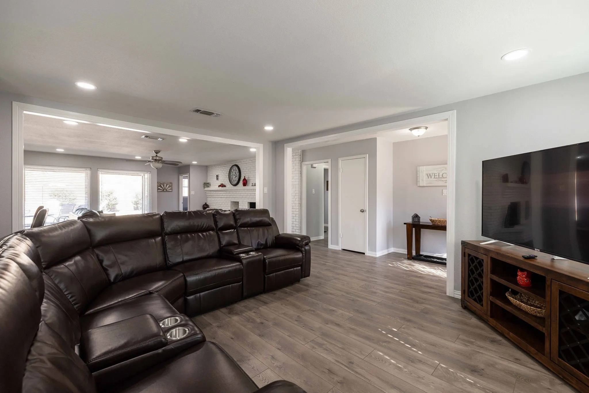 Living room with a ceiling fan, wood finished floors, recessed lighting, baseboards, and a brick fireplace