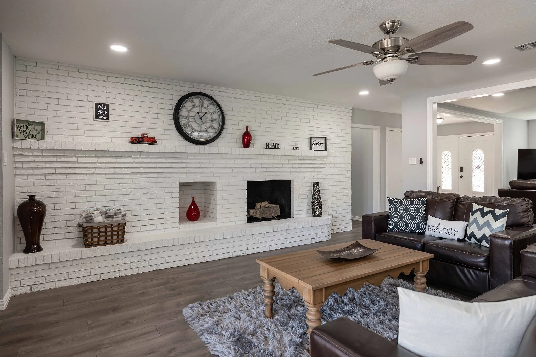 Living area featuring ceiling fan, wood finished floors, brick wall, a brick fireplace, and recessed lighting