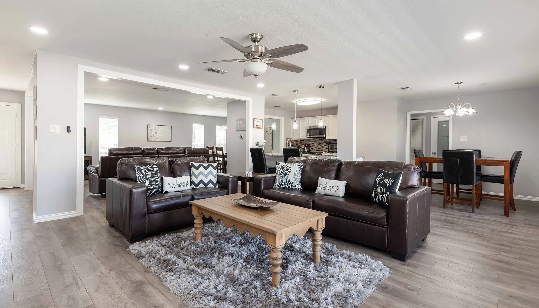 Living room with light wood-type flooring, a ceiling fan, baseboards, a chandelier, and recessed lighting