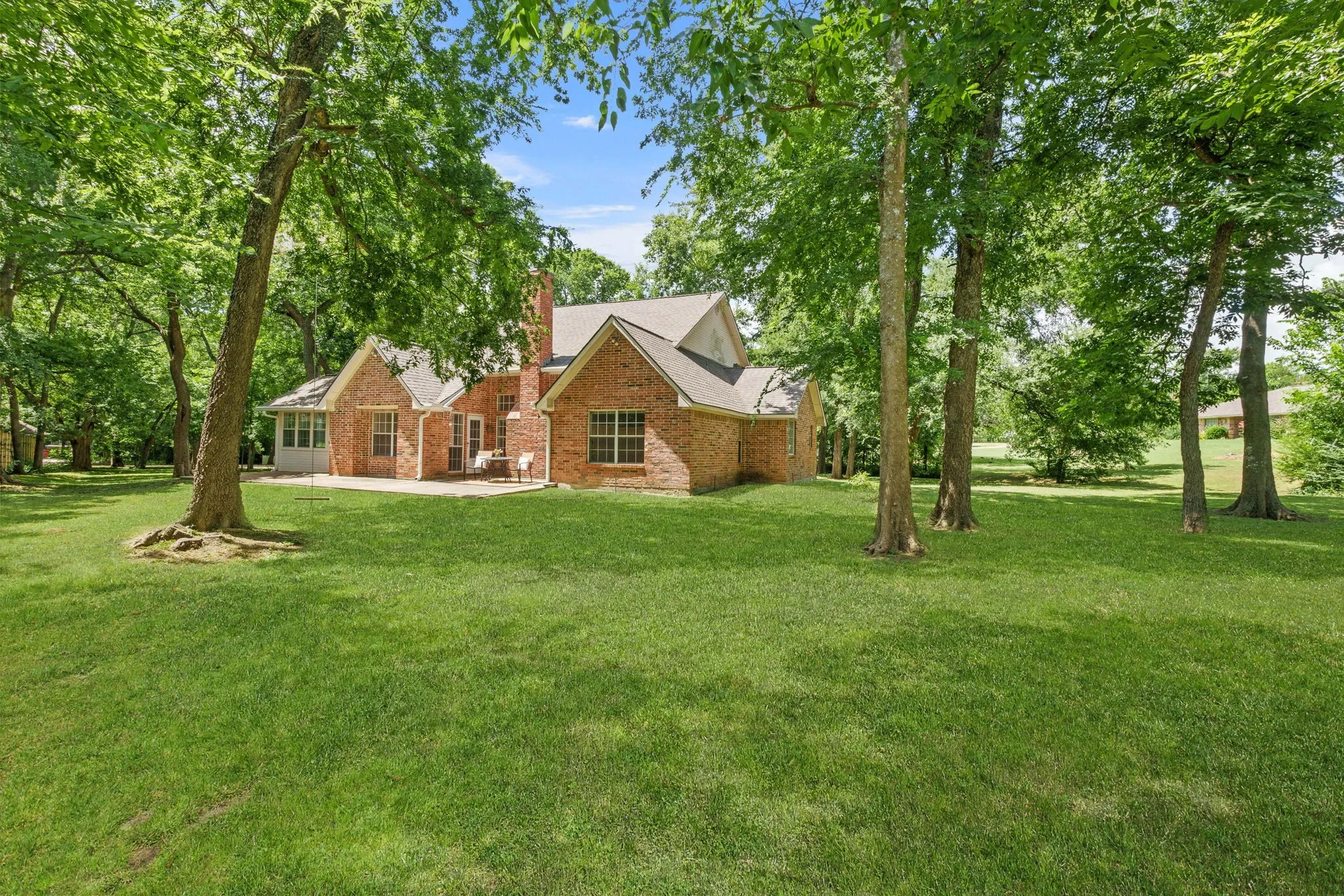 Outdoors, enjoy a covered front porch, extended back patio shaded by mature trees, sprinkler system, storage building, fire pit, and a side-yard garden area framed with landscape timbers.