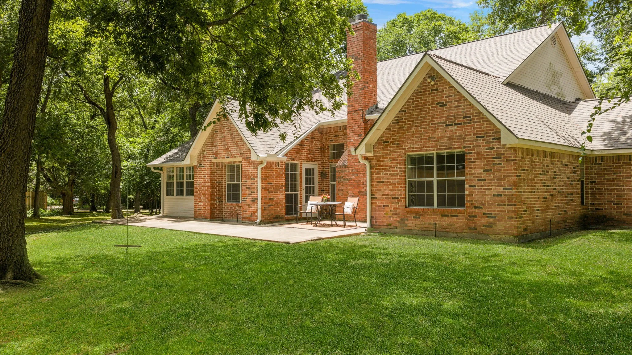 Extended back patio shaded by mature trees.