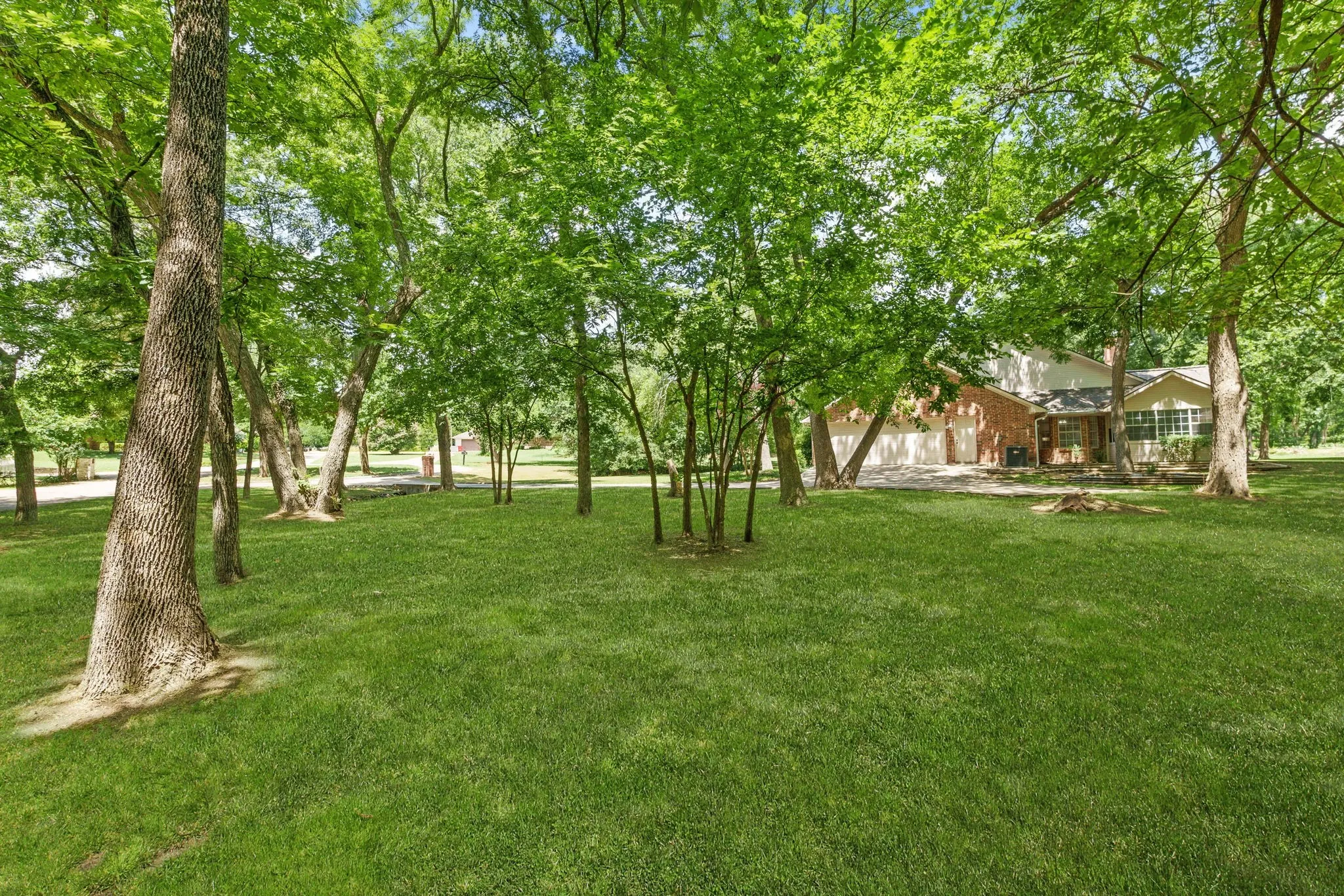 Outdoors, enjoy a covered front porch, extended back patio shaded by mature trees, sprinkler system, storage building, fire pit, and a side-yard garden area framed with landscape timbers.