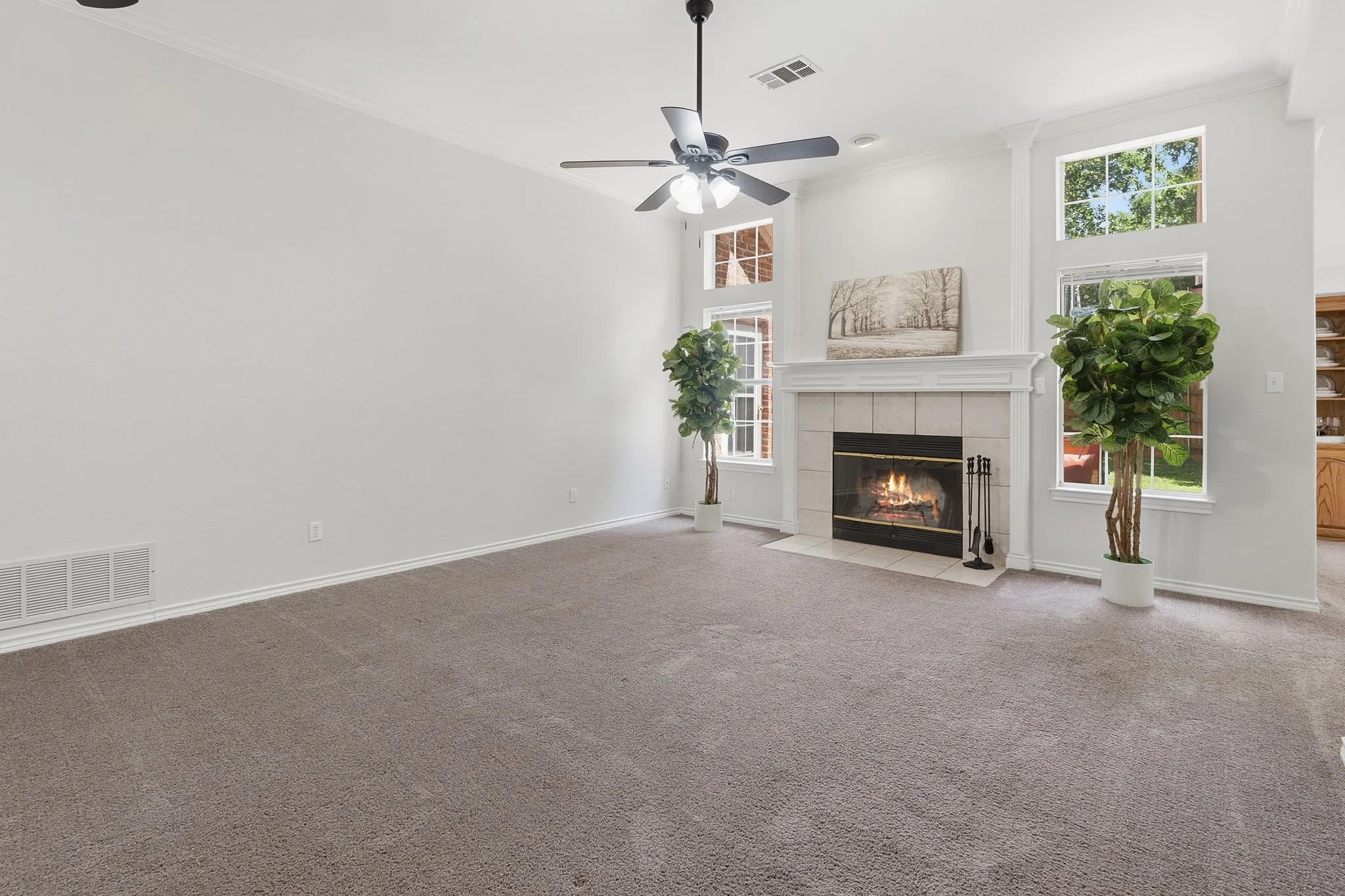 Spacious family room features a wood-burning fireplace with blower, generous windows, and two ceiling fans.