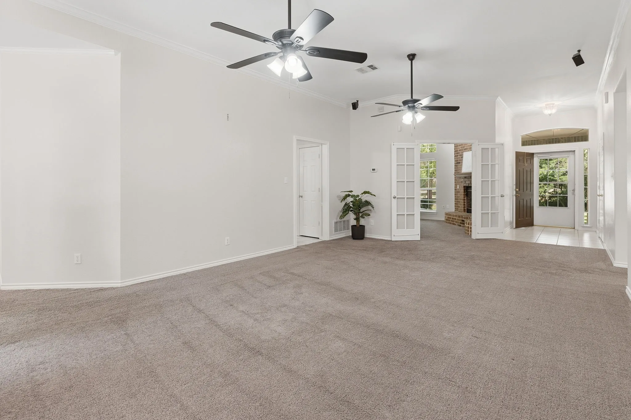 Spacious family room features a wood-burning fireplace with blower, generous windows, and two ceiling fans.