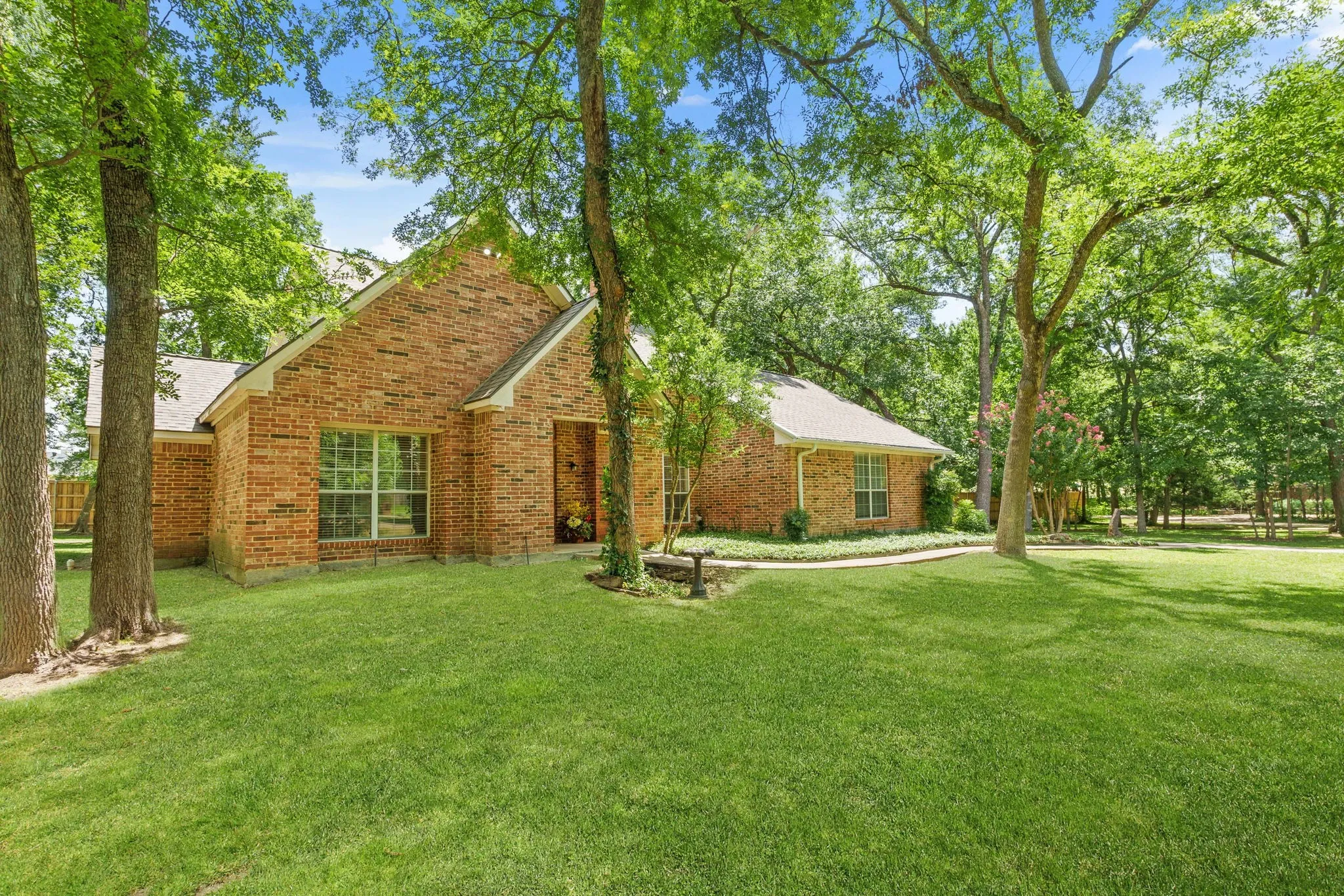 Outdoors, enjoy a covered front porch, extended back patio shaded by mature trees, sprinkler system, storage building, fire pit, and a side-yard garden area framed with landscape timbers.