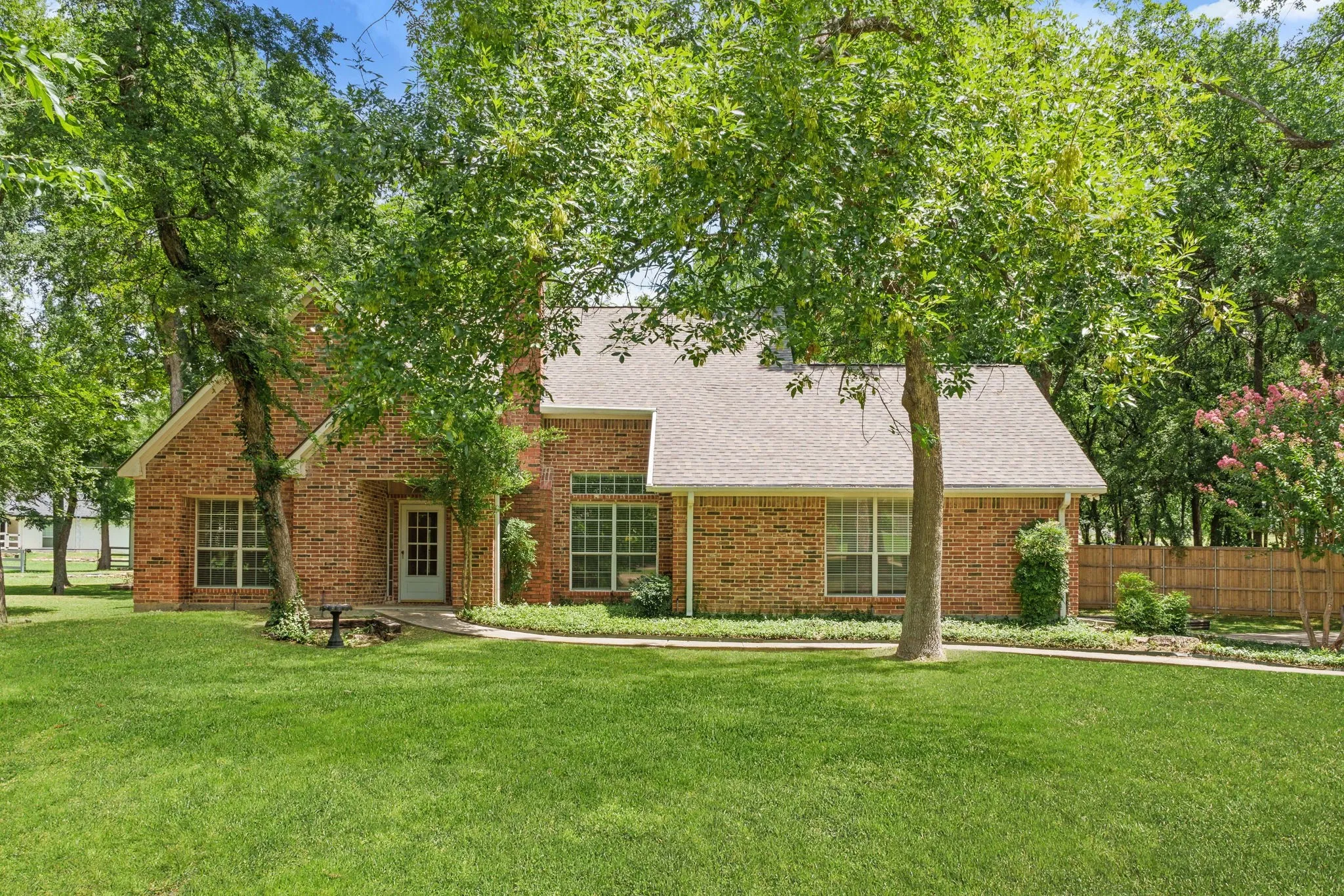 Outdoors, enjoy a covered front porch, extended back patio shaded by mature trees, sprinkler system, storage building, fire pit, and a side-yard garden area framed with landscape timbers.
