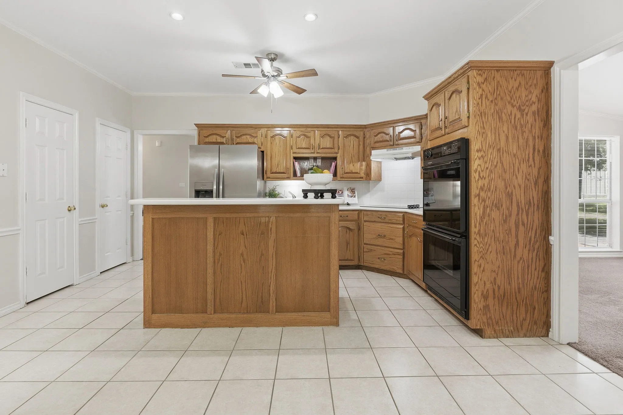 The kitchen offers custom wood cabinetry, electric appliances, double ovens, a serving bar, great cabinet space, and two pantries.