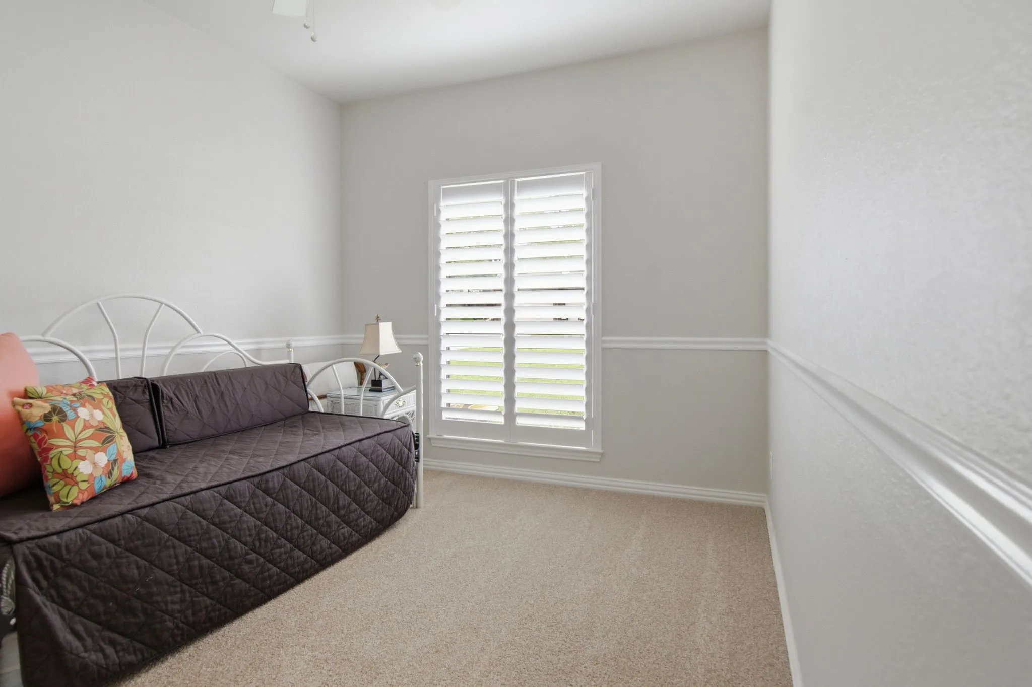 Secondary bedroom with decorative chair rail, plantation shutters, and walk-in closet.