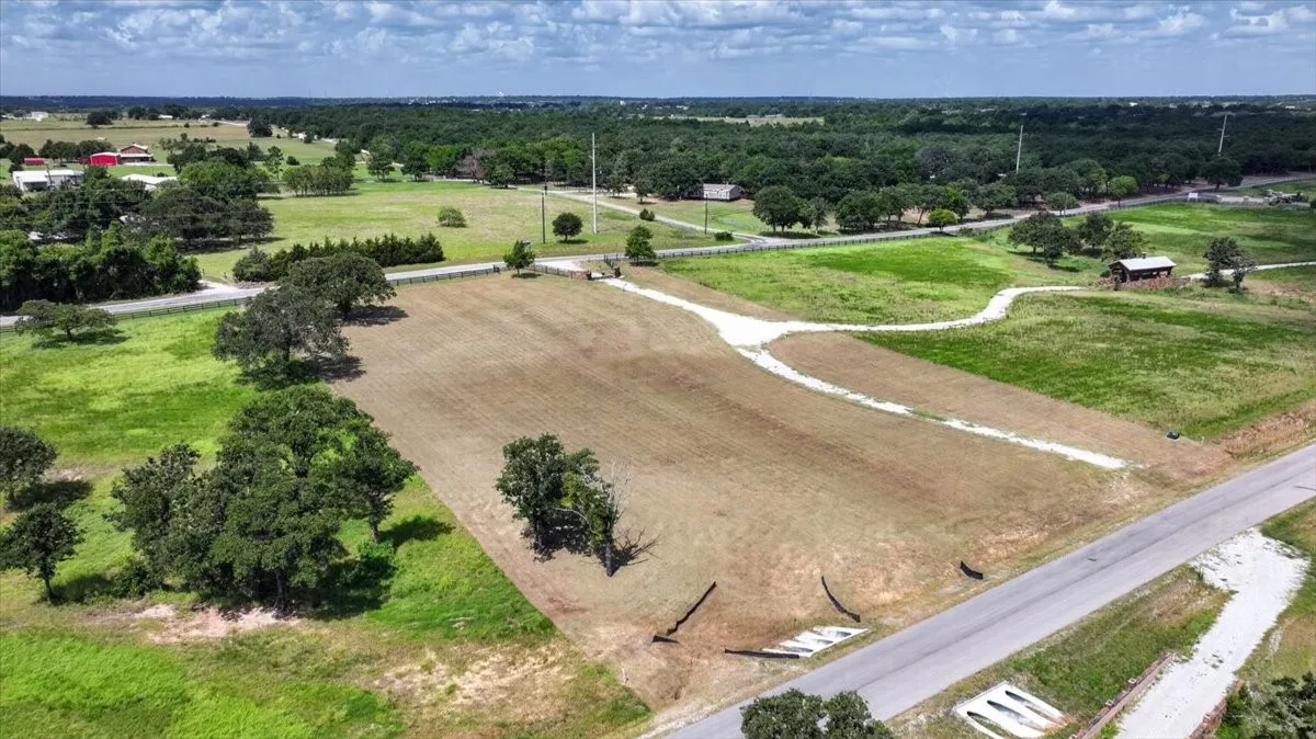 Expansive land parcel featuring partial clearing, mature trees, and direct road frontage