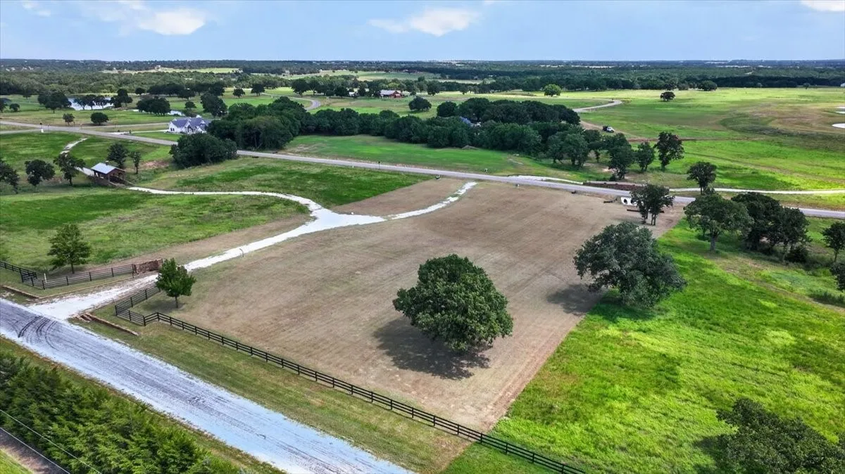 Expansive undeveloped lot featuring mature trees and a clear perimeter fence
