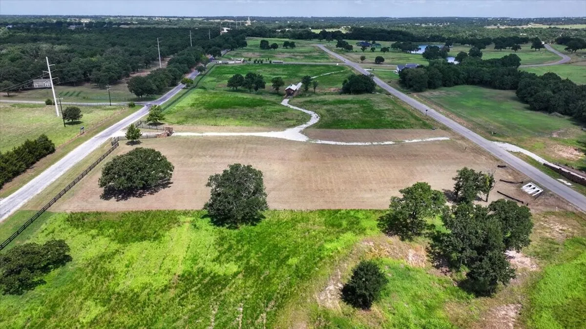 Expansive land parcel featuring open fields, scattered mature trees, and direct road frontage
