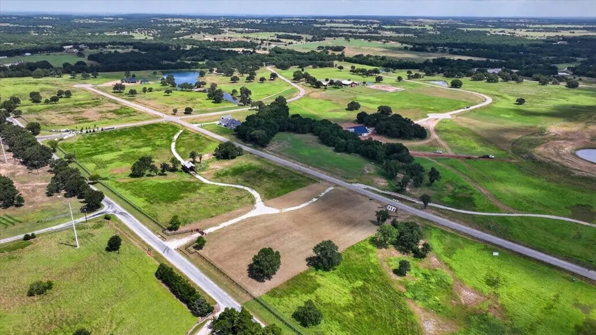 Expansive rural landscape featuring multiple parcels, scattered mature trees, and a visible pond