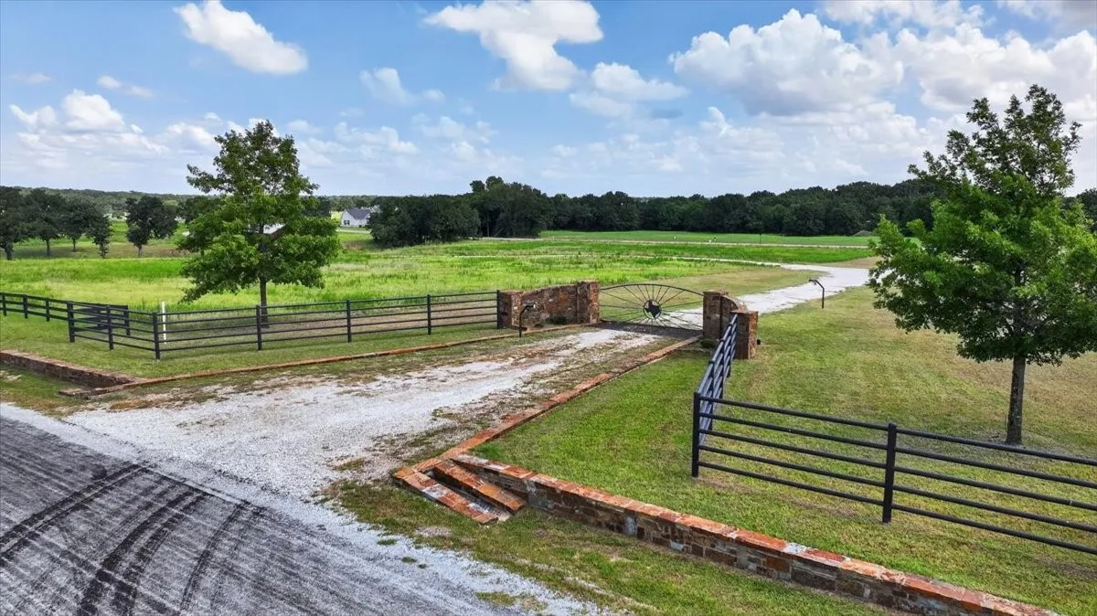 Gated entry with stone columns opening to a gravel driveway