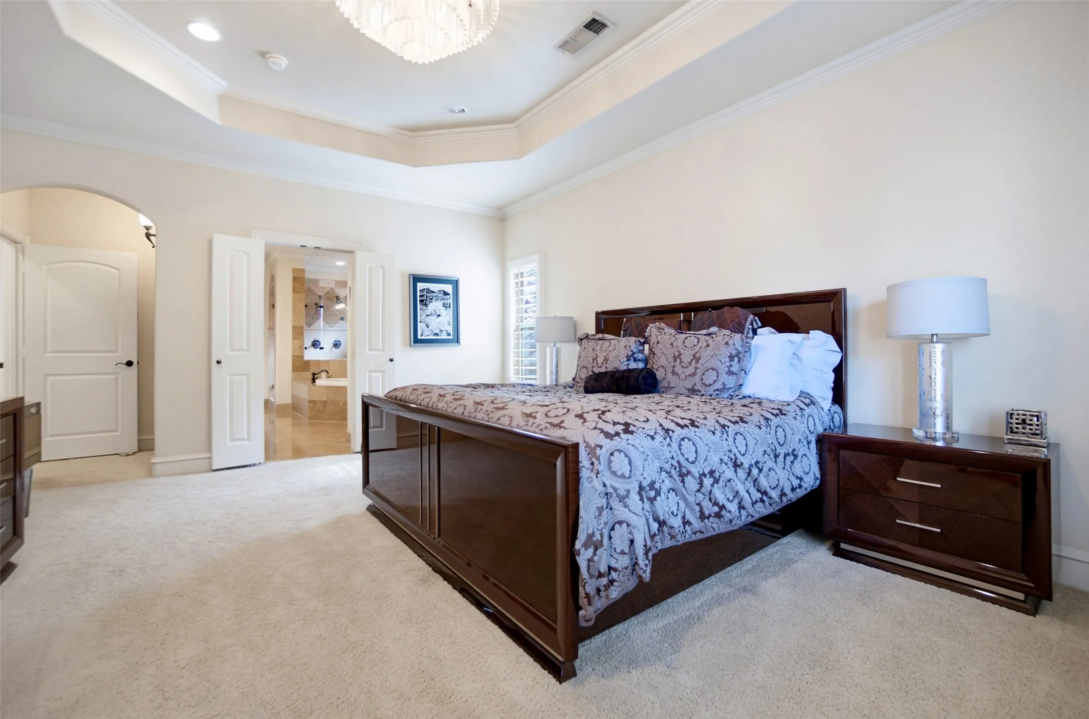 Spacious bedroom featuring plush carpet flooring and a tray ceiling with crown molding