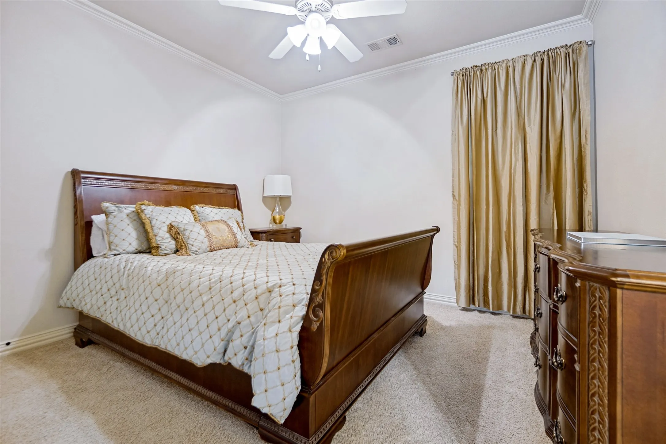 Interior room featuring carpeting, crown molding, a ceiling fan, and a window with drapery