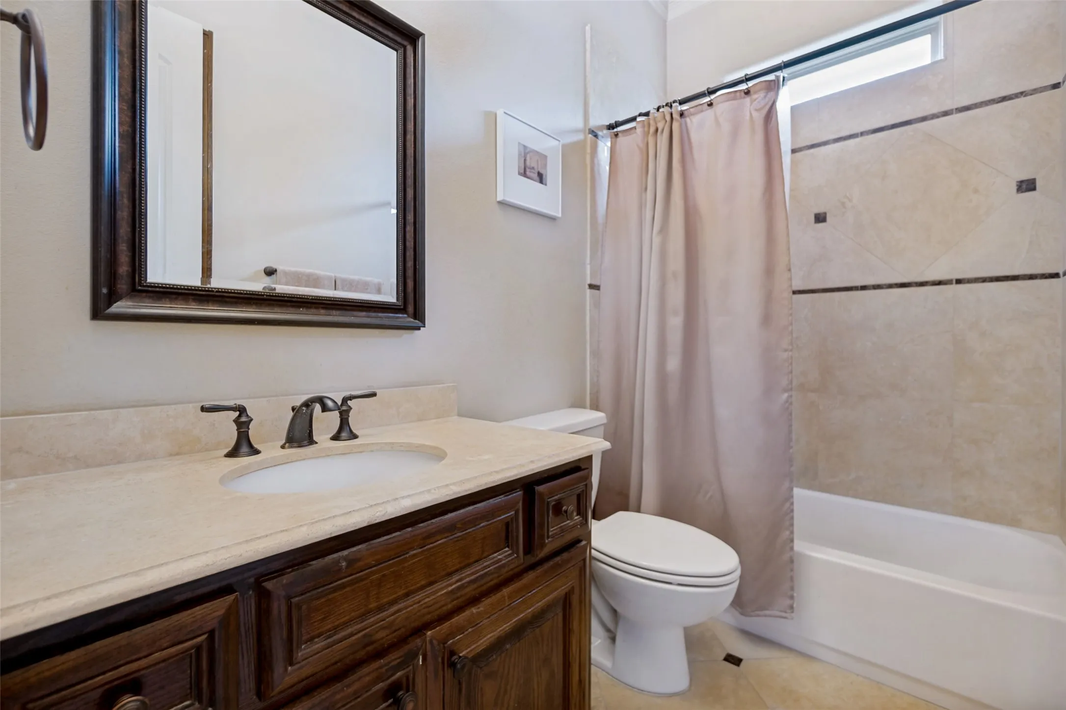 Downstairs full bathroom vanity featuring a light-toned countertop, dark wood-finish cabinetry, and an undermount sink